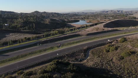 Autopista-Con-Tráfico-Ligero,-Lago-Y-Naturaleza-Al-Fondo