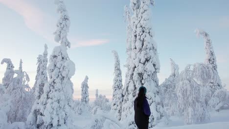 Girl-Walking-Up-Street,-Explores-Beautiful-Snow-Covered-Winter-Wonderland-in-Lapland,-Finland,-Arctic-Circle