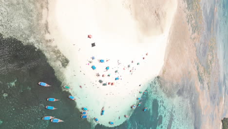 Aerial-view-of-boats-on-Zanzibar's-turquoise-water-and-people-enjoying-the-weather-on-a-sandbank