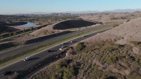 Static-Shot-of-Freeway-with-Steady-Traffic,-Surrounded-by-Trees-with-a-Lake-in-the-Distance
