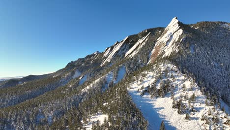 Slow-aerial-Drone-Rise-of-Colorado-flatirons-and-chautauqua-park-in-Boulder,-Colorado-on-a-bright-winter-morning-with-snow