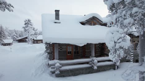 Drohne-Fliegt-Auf-Und-über-Das-Schneebedeckte-Dach-Einer-Hütte-In-Lappland,-Finnland,-Polarkreis