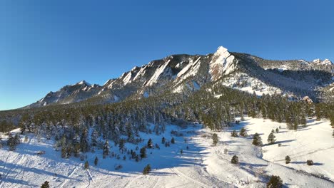 Aerial-Drone-Reversing-away-from-the-famous-Flatiron-Mountains-in-Boulder,-Colorado,-USA-on-a-winter-morning-day-after-a-snow-storm