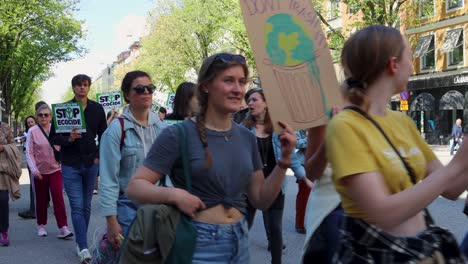 Crowd-of-diverse-people-marching-in-environmental-rally,-holding-signs,-during-the-day-in-Stockholm
