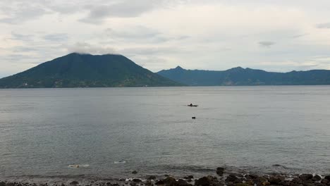 Person-Paddelt-Mit-Einem-Kleinen-Fischerboot-Auf-Der-Insel-Alor-Mit-Vulkanischer-Tropischer-Insel-In-Der-Ferne-Auf-Den-östlichen-Kleinen-Sunda-Inseln-Im-Osten-Von-Nusa-Tenggara