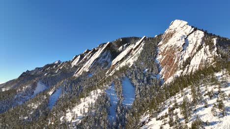 Dramatic-Aerial-Drone-pan-of-the-Flatiron-mountains-covered-in-snow-in-Boulder,-Colorado,-USA-on-a-winter-morning