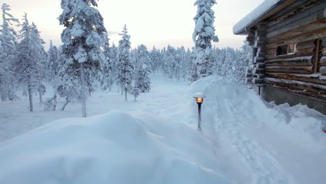 Snowy-Winter-Wonderland-Landscape,-With-Cabin,-and-Landscape-Lights-In-Lapland,-Finland,-Arctic-Circle