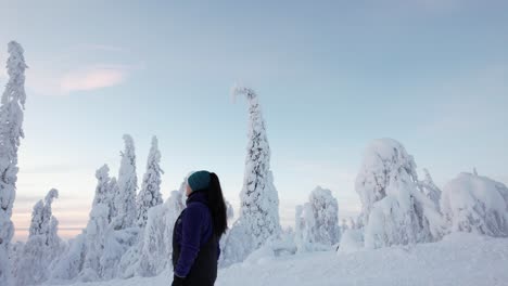 Girl-Walking-and-Exploring-Winter-Wonderland-Landscape-with-Huge-Snow-Covered-Trees-in-Lapland,-Finland,-Arctic-Circle