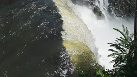Iguazu-Falls-Waterfall-in-Argentina,-Slow-Motion-Panning-View-of-Watefall-River-Falling-off-Tall-Rainforest-Cliff,-Scenery-of-Clear-Colourful-Water-Crashing-into-Plunge-Pool-in-Iguacu,-South-America