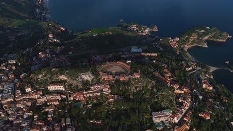 Taormina-ancient-greek-theatre-aerial,-Sicily-coast-village-on-mountain-in-Italy
