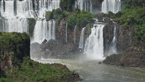 Hermosa-Y-Tranquila-Vista-De-Cascadas-En-Cámara-Lenta-Que-Se-Acumulan-En-Un-Increíble-Arroyo-De-Piscina-En-Una-Selva-Verde,-Muchas-Cascadas-Dobles-Chocando-Contra-Un-Paisaje-Rocoso-Húmedo-En-Las-Cataratas-Del-Iguazú,-Brasil