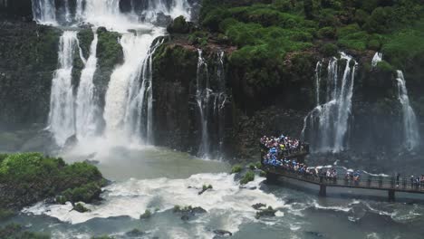 Iguazu-Falls-Waterfall-in-Brazil,-Amazing-Tourist-Destination-View-from-Platform-Looking-over-Beautiful-Slow-Motion-Falling-Huge-Waterfalls-Crashing-and-Splashing-into-People-Watching