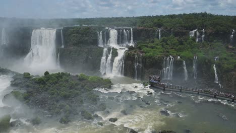 High-Above-View-of-Amazing-Tourism-Destination-of-Tall-Rough-Waterfalls-in-Rough-Rocky-Jungle-Landscape,-Tourist-Platform-Viewing-Close-Up-Huge-Splash-Zone-Hidden-in-Iguazu-Falls
