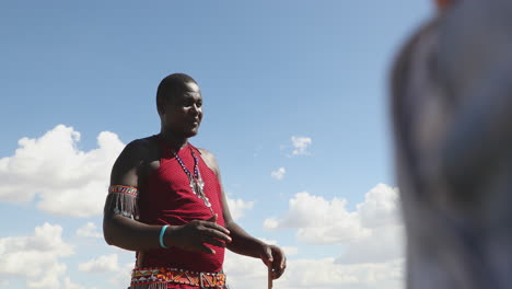 Maasai-Man-In-Traditional-Clothes-Talking-To-Group-Of-Tourists-At-Maasai-Mara-In-Kenya