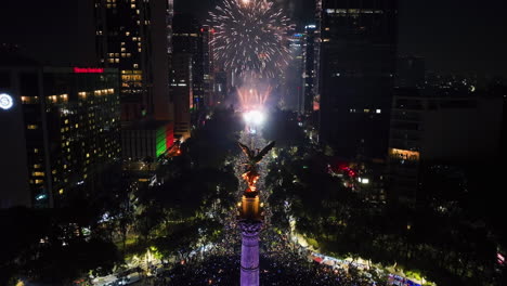 Aerial-view-away-from-the-illuminated-El-Ángel-de-la-Independencia-statue,-fireworks-in-CDMX