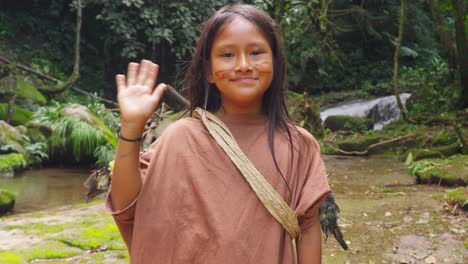 Young-indigenous-girl-waving-in-rainforest,-traditional-attire,-Oxapampa,-Peru,-waterfall-background