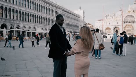Mixed-race-couple-holding-handy-and-flirting-with-each-other-on-piazza-di-San-Marco-near-Palazzo-Ducale-in-Venice-Italy---the-love-can-be-felt-even-with-all-the-tourists-around-on-a-sunny-day