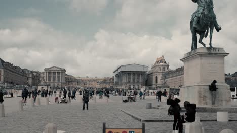 Statue-Von-König-Ludwig-XIV.-Auf-Einem-Pferd-Vor-Dem-Berühmten-Schloss-Versailles,-Paris,-Frankreich,-Mit-Einem-Wunderschönen-Blauen-Himmel-Und-Wolken,-Während-Sich-Viele-Touristen-Und-Menschen-Um-Das-Schloss-Drängen-–-Filmische-Weitwinkelaufnahme