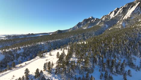 Aerial-Drone-pan-of-snowy-winter-landscape-with-trees-and-flatiron-Mountains-in-Boulder,-Colorado,-USA