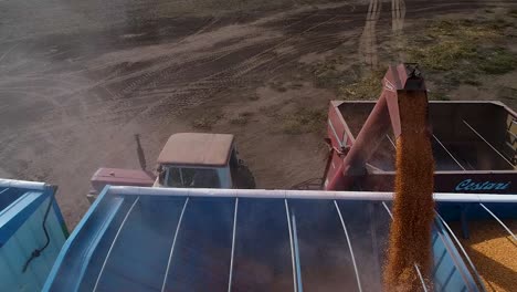 Grain-being-loaded-into-a-truck-at-a-rural-silo,-clear-sky,-aerial-view