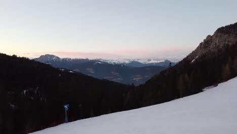 Wanderer-Auf-Einem-Schneebedeckten-Hügel-Mit-Leerem-Skihang-Und-Blick-Auf-Den-Sonnenuntergang-über-Den-Bergen
