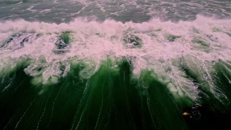 Forceful-ocean-wave-crashing-near-coastline,-aerial-view