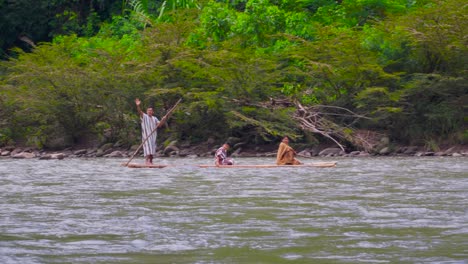 Indigenous-people-on-a-traditional-raft-on-a-river-in-Oxapampa,-Peru,-surrounded-by-lush-greenery