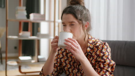 Close-up-of-dark-haired-woman-drinking-tea-in-living-room,-slo-mo