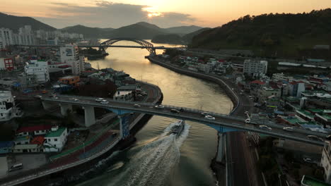 Aerial-view-of-a-boat-sailing-towards-a-sunset-in-Tongyeong,-South-Korea,-a-coastal-city-located-in-Gyeongsang-Province