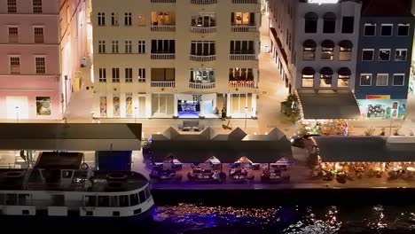 High-angle-overview-along-Handelskade-waterfront-buildings-and-ferry,-Curacao-at-night