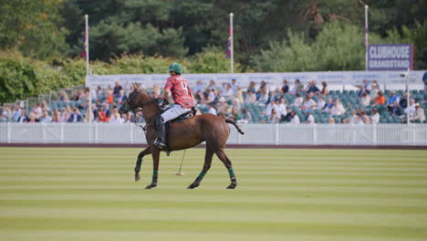 Polo-player-canters-along-on-horse,-riding-on-green-field,-waiting-for-match-to-start