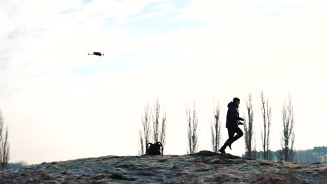 Person-run-on-rocky-frozen-hill-while-drone-follow-in-air,-bright-background