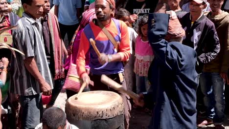 Hombres-Timorenses-Tocando-Tambores-Tradicionales-Con-Gente-Local-De-La-Comunidad-Bailando-Y-Observando-Durante-Una-Ceremonia-De-Bienvenida-En-Timor-Oriental,-Sudeste-De-Asia