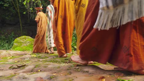 Barefooted-individuals-in-colorful-garments-walking-on-a-forest-path