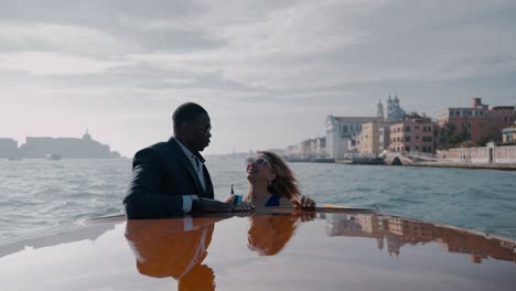 Ein-Gemischtrassiges-Paar-Macht-Eine-Bootsfahrt-In-Venedig,-Italien,-Genießt-Die-Malerische-Aussicht-Und-Küsst-Sich-An-Einem-Sonnigen-Tag-Voller-Freude