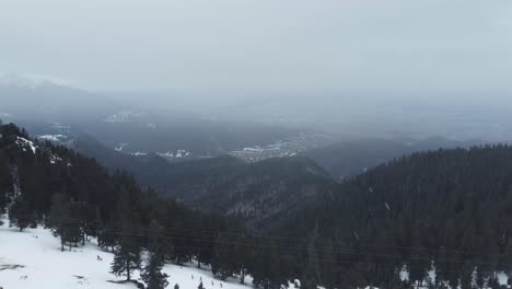 Unglaubliche-Drohnenaufnahme-Aus-Der-Luft-Von-Bergen-Voller-Kiefern-Und-Schnee,-Während-Eines-Schneefalls-Im-Winter