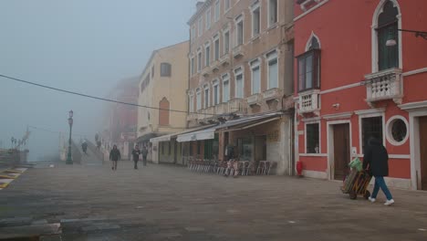 Misty-Venetian-street-in-early-morning-light,-Locals-commute