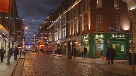 Dämmerungsszene-Auf-Einer-Belebten-Straße-In-Dublin,-Geschmückt-Mit-Festlichen-Lichtern,-Menschen,-Die-Spazieren-Gehen