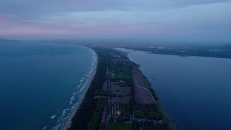 Twilight-hues-over-a-calm-coastal-landscape-with-gentle-waves,-aerial-view
