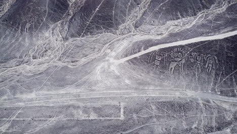 Top-down-aerial,-desert-plateau-landscape-with-the-Nazca-lines-and-humanoid-creatures,-historical-landmark-in-Peru