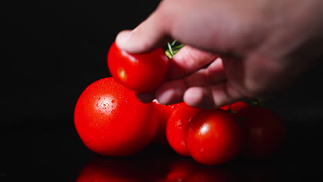 Side-view-of-a-male-hand-picking-up-a-tomato-from-a-stack-of-tomato-in-slow-motion