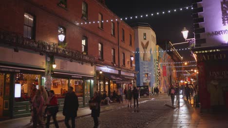 Abendansicht-Einer-Belebten-Straße-In-Dublin,-Gesäumt-Von-Festlichen-Lichtern-Und-Geschäftigen-Fußgängern