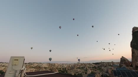 Zeitrafferaufnahme-Einiger-In-Der-Luft-Fliegender-Heißluftballons-Inmitten-Natürlicher-Felsstrukturen-Und-Künstlicher-Unterkünfte-In-Kappadokien,-Türkei