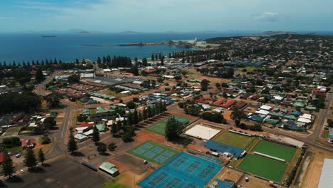 Luftbild,-Das-Die-Stadt-Esperance-In-Westaustralien-Mit-Tennisplätzen-Im-Vordergrund-Und-Dem-Hafen-Im-Hintergrund-An-Einem-Sonnigen-Tag-Zeigt