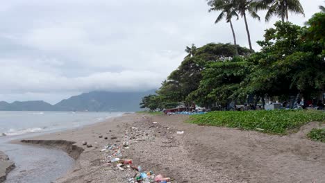 Lines-of-plastic-rubbish-and-other-trash-left-on-beach-from-ocean-high-tide-in-capital-city-of-East-Timor,-Southeast-Asia