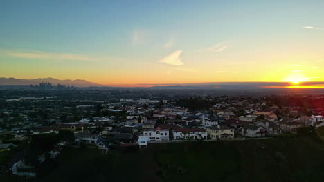 Aerial-drone-shot-of-sun-rising-over-houses-in-Kenneth-Hahn-Recreational-Area-during-morning-time-in-Los-Angeles,-CA,-USA