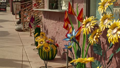 Fake-flowers-in-downtown-Sedona,-Arizona-with-video-tilting-up-to-people-walking-on-the-streets