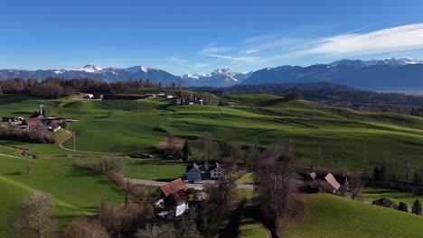 Wunderschöne-Grüne-Hügel-Mit-Kleinem-Schweizer-Dorf-An-Sonnigen-Tagen