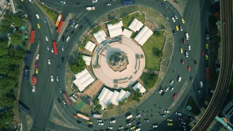 4K-Cinematic-urban-drone-footage-of-an-aerial-panoramic-smoky-view-of-the-Victory-Monument-roundabout-in-the-middle-of-downtown-Bangkok,-Thailand-during-burning-season