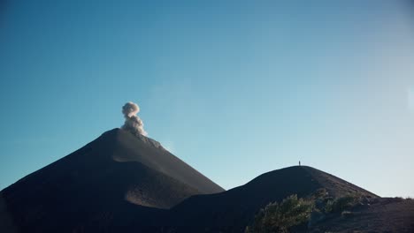 Single-person-standing-on-ridge-of-erupting-Fuego-Volcano